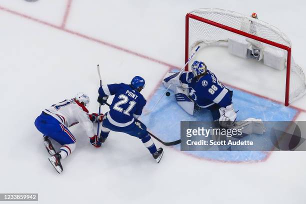 Goalie Andrei Vasilevskiy of the Tampa Bay Lightning makes a save as teammate Brayden Point and Eric Staal of the Montreal Canadiens look for the...