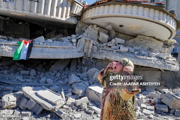 Palestinian woman reacts outside a building that belonged to Montasser Shalabi, who was arrested in May on suspicion of carrying out a drive-by...