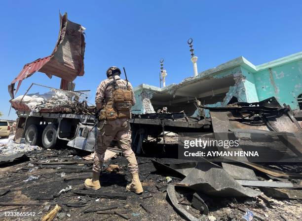 Member of the Iraqi security forces walks past a destroyed vehicle that was carrying rockets amdist sacks of flour, in the district of al-Baghdadi in...
