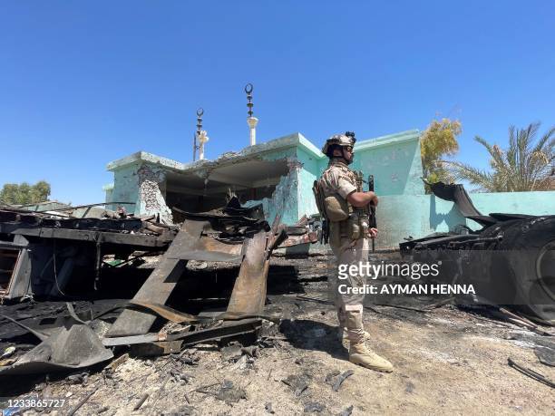 Member of the Iraqi security forces stands by a destroyed vehicle that was carrying rockets amdist sacks of flour, in the district of al-Baghdadi in...