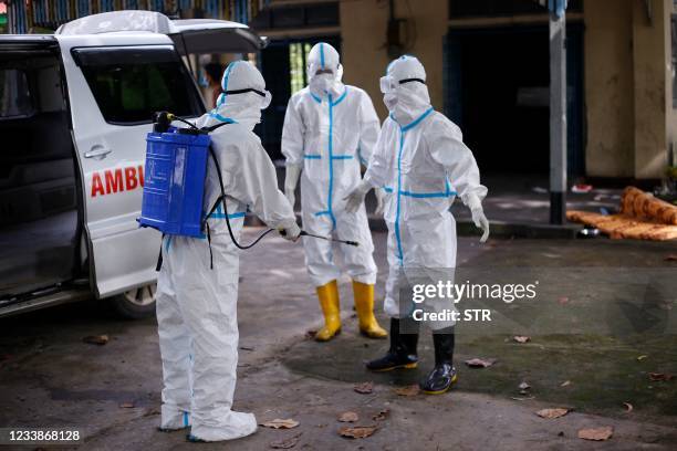 Volunteer wearing personal protective equipment is sprayed with disinfectant as they cremate the bodies of people who died from the Covid-19...