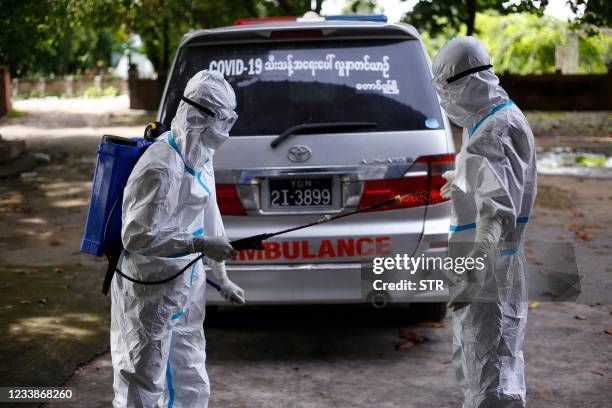 Volunteer wearing personal protective equipment is sprayed with disinfectant as they cremate the bodies of people who died from the Covid-19...