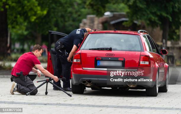 July 2021, Lower Saxony, Hanover: Hendrik Vorreiter of the Hanover police is measuring the volume of a car with a sound level meter. Police officers...