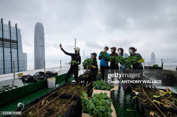 In this picture taken on April 9 Rooftop Republic urban farmers pose with harvested vegetables grown on a rooftop farm at the top of the 150-metre...