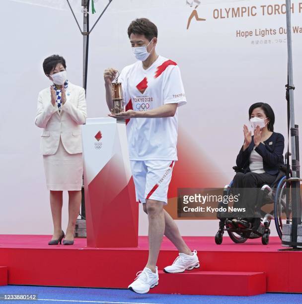 Former tennis pro Shuzo Matsuoka holds the lantern containing the Olympic flame during a ceremony marking the start of the Tokyo leg of the Tokyo...