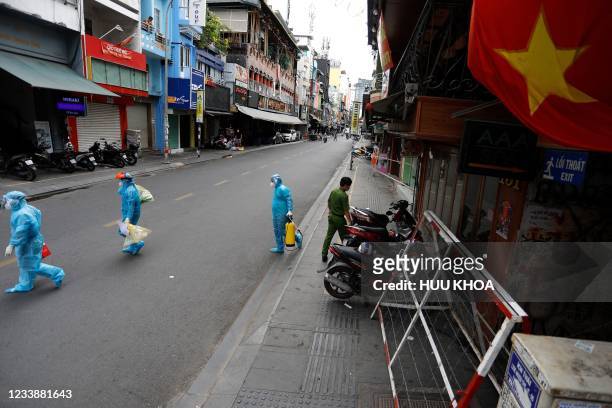 Medical workers collecting test samples from residents walk past in Ho Chi Minh City on July 9 on the first day of the government imposed two-week...