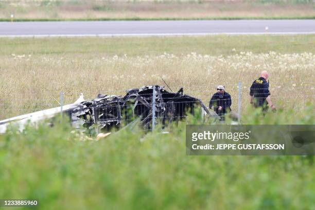 Police officers investigate the plane wreck outside Orebro Airport on July 9, 2021. - Swedish police said that all nine people aboard a small...