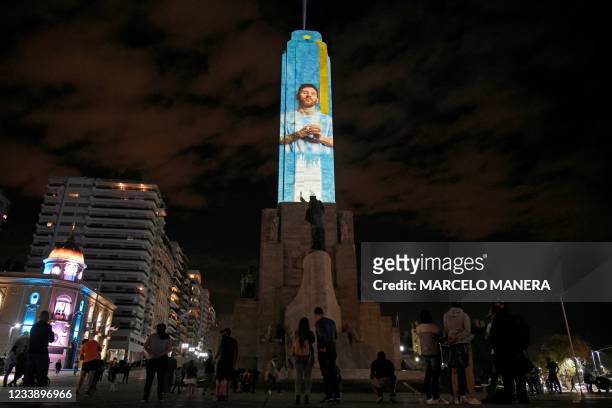 People look at the Flag's monument with an image of Argentine football star Lionel Messi's image projected on it, as part of a video mapping in...