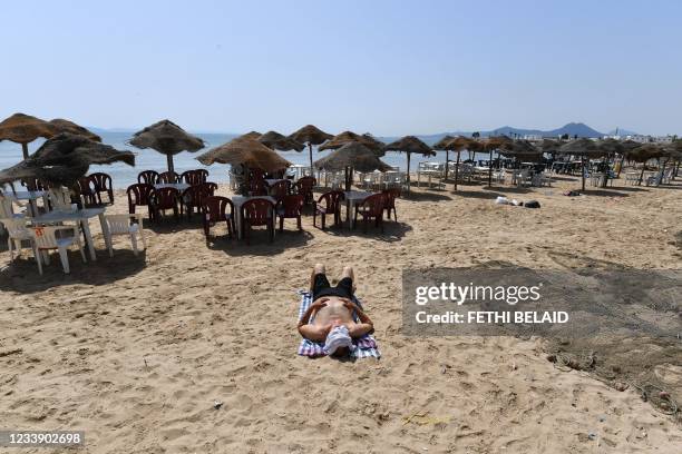 Man lies on a nearly deserted beach during a lockdown was imposed by the Tunisian authorities as a measure against the spread of coronavirus...