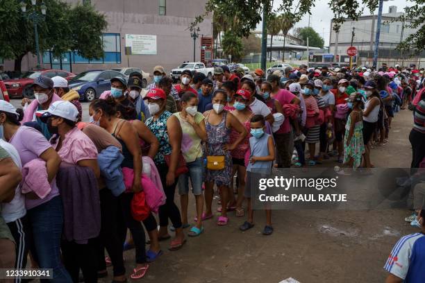 Migrants wait in line for clothes and supplies in a makeshift migrant camp in the border town of Reynosa, Tamaulipas, Mexico on July 10, 2021. -...