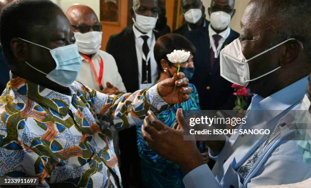 Former Ivorian presidents Henri Konan Bedie offers a carnation to Laurent Gbagbo as he welcomes him to his residence in the city of Daoukro in Ivory...