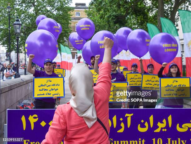 Protester gesturing leads a group of demonstrators holding placards among balloons with the slogan 'Free Iran London' during the Free Iran World...
