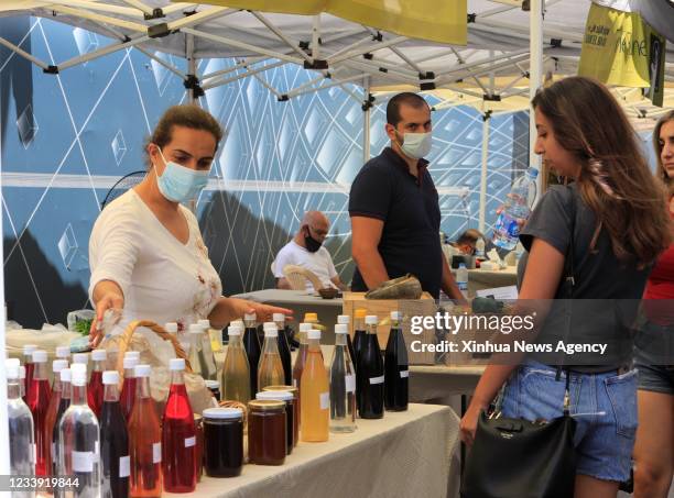 Woman describes home-made drinks to a customer at a community service market in downtown Beirut, Lebanon, on July 10, 2021.