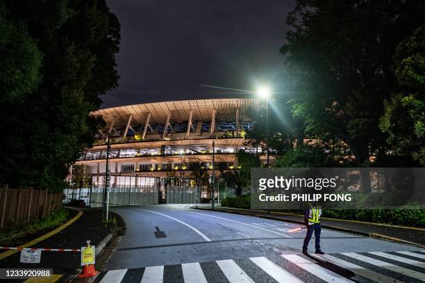Security personnel stands guard in front of the National Stadium, the main venue for the Tokyo 2020 Olympic and Paralympic Games, in Tokyo on July...