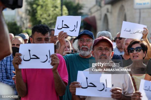 Palestinian demonstrators lift placards in Arabic addressing Palestinian President Mahmoud Abbas which read "Leave", during a rally in Ramallah city...