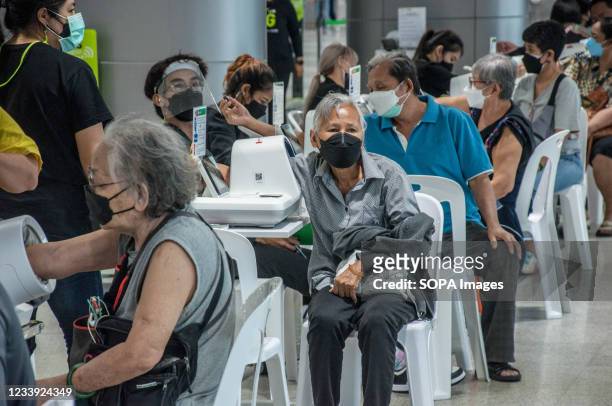 People check their blood pressure before receiving a shot of AstraZeneca during a vaccination against COVID-19 at Bang Sue Grand Station in Bangkok....