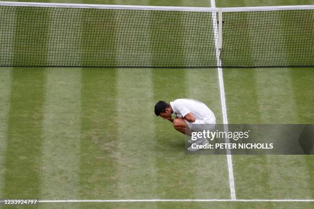 Serbia's Novak Djokovic eats grass as he celebrates winning against Italy's Matteo Berrettini during their men's singles final match on the...