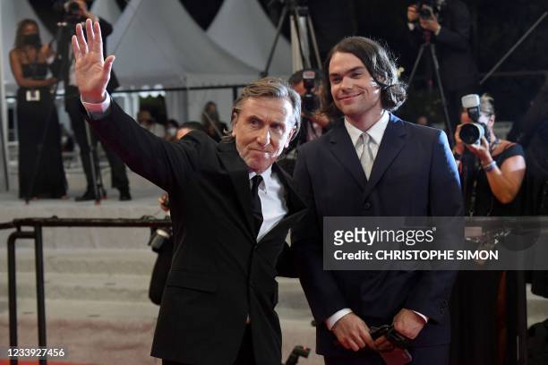 British actor Tim Roth waves as he arrives with his son Michael Cormac Roth for the screening of the film "Bergman Island" at the 74th edition of the...