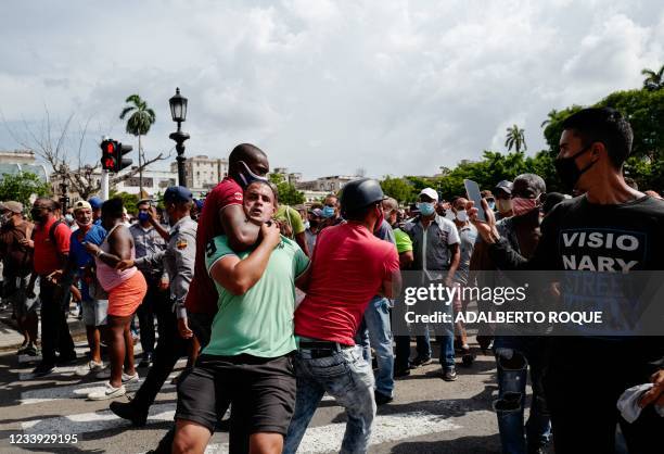 Man is seized by his neck during a demonstration against the government of Cuban President Miguel Diaz-Canel in Havana, on July 11, 2021. - Thousands...