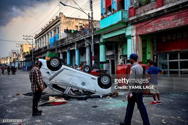 Police cars are seen overturned in the street in the framework of a demonstration against Cuban President Miguel Diaz-Canel in Havana, on July 11,...