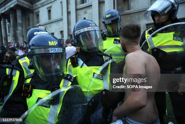 An England fan argues with police officers as riot police secure the area around the fan zone. England fans break through barriers to watch the match...