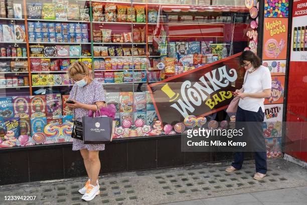Wonka bar in a sweet shop window as two women check their smartphones on 2nd July 2021 in London, United Kingdom. Willy Wonka & the Chocolate Factory...