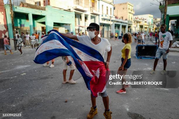 Man waves a Cuban flag during a demonstration against the government of Cuban President Miguel Diaz-Canel in Havana, on July 11, 2021. - Thousands of...