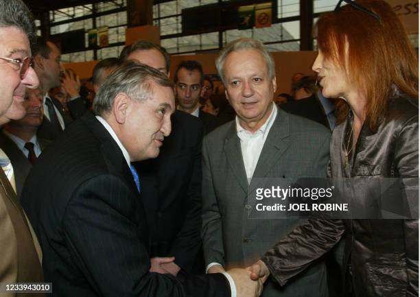 Le Premier ministre Jean-Pierre Raffarin sert la main le 20 mars 2003, à Paris, la main de la directrice de France Culture Laure Adler en compagnie...