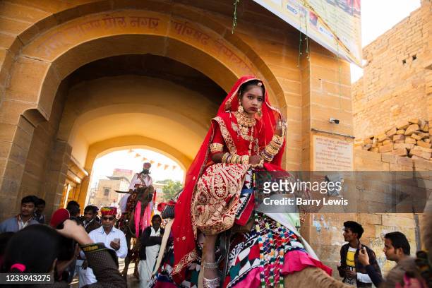 Parading on the back of a camel, a Rajasthani women in traditional bridal costume at the Desert Festival on 29th January 2018 in Jaisalmer,...