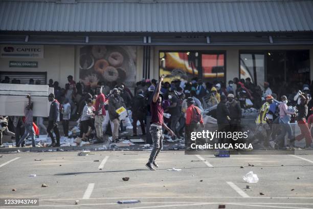 Man gestures as rioters loot the Jabulani Mall in the Soweto district of Johannesburg on July 12, 2021. South Africa said it was deploying troops to...