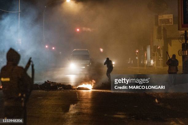 South Africa Police Service officer aims his rifle at a in incoming minivan bringing it to a stop in Jeppestown, Johannesburg, on July 12, 2021...