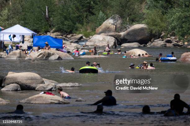 People cool off in the Kern River, which is running at about one quarter capacity toward Lake Isabella, as a heatwave brings a temperature of 106...