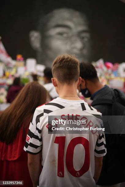 Young man in a Rashford football shirt looks at the messages of support displayed at the newly repaired mural of England footballer Marcus Rashford...