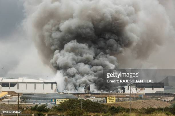 Smoke rises from a Makro building set on fire overnight in Umhlanga, north of Durban, on July 13, 2021 as several shops, businesses and...
