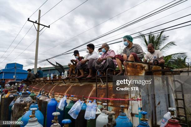 This picture taken on July 13, 2021 shows people waiting to fill up empty oxygen canisters outside a factory in Mandalay, amid a surge in Covid-19...