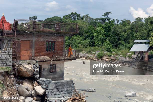 Woman clears the debris from her house which was damaged due to a flash flood after heavy rain in Dhauladhar Range at Village Sheela.