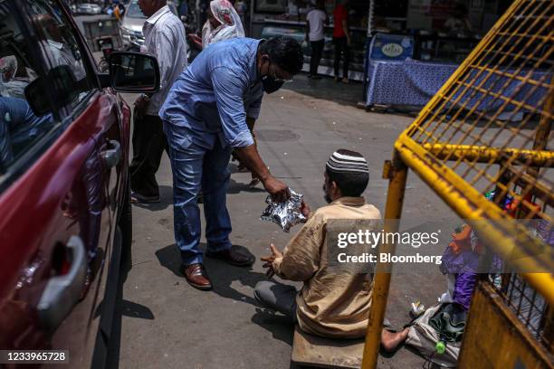 Volunteer for Khana Chahiye, or Want Food collective, distributes free food packs on the street to those in need in Mumbai, India, on Wednesday, Jul...