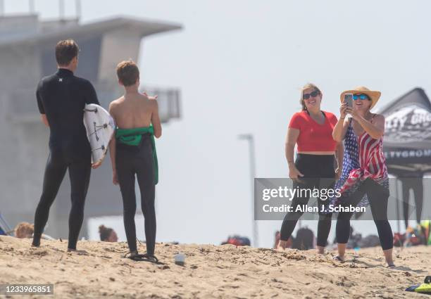 Huntington Beach, CA USA Surfing Team member Kolohe Andino of San Clemente, poses for a photo with a young fan as Brett Simpson, of Huntington Beach,...