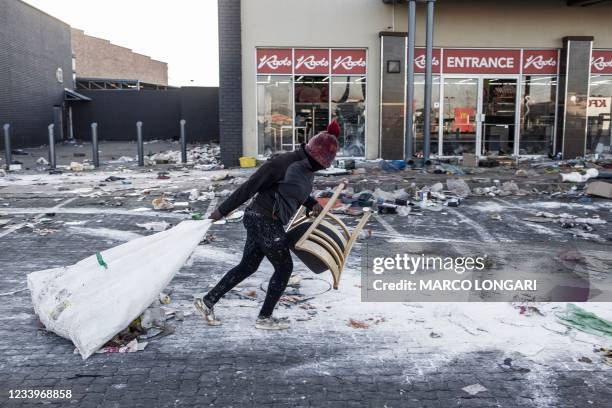 Suspected looter pulls a few items along the ground outside a vandalised mall in Vosloorus, on the outskirts of Johannesburg, on July 14, 2021....