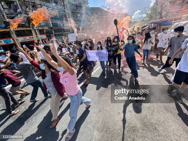 Women holding banners, emergency flare sticks and fire sticks as they march during a demonstration against the military coup in Yangon on July 14,...