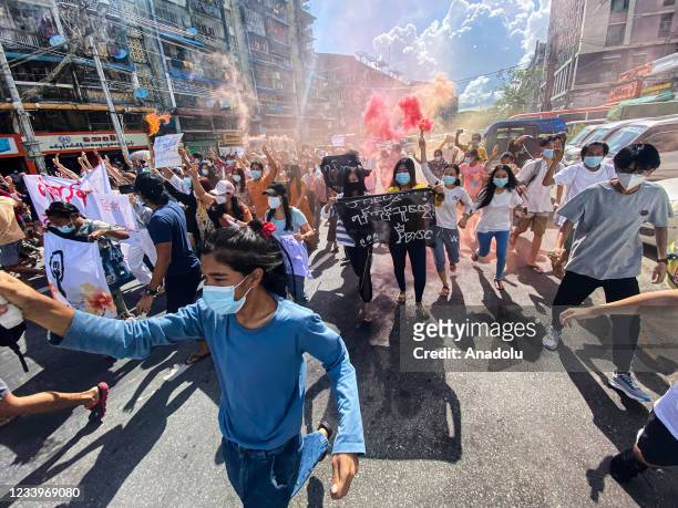 Women holding banners, emergency flare sticks and fire sticks as they march during a demonstration against the military coup in Yangon on July 14,...