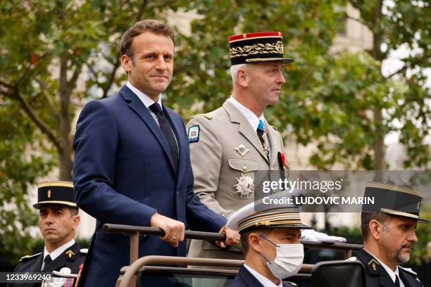 French President Emmanuel Macron and French Armies Chief of Staff General Francois Lecointre stand in the command car as they review troops prior to...