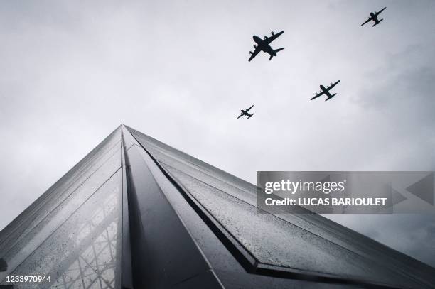 An Airbus A400M Atlas , next to Lockheed Martin C-130J Super Hercules and two CASA CN-235 fly over the Louvre Pyramid during the annual Bastille Day...