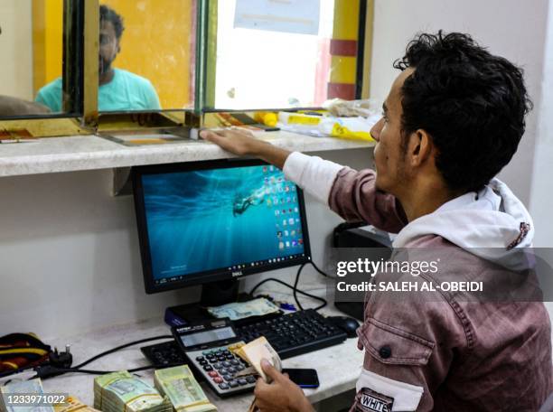 An employee serves customers at an exchange counter in the southern Yemeni city of Aden on July 14 where the value of the local currency has sunk to...