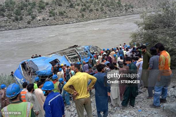 Rescue workers and onlookers gather around a wreck after a bus plunged into a ravine following a bomb explosion, which killed 12 people including 9...