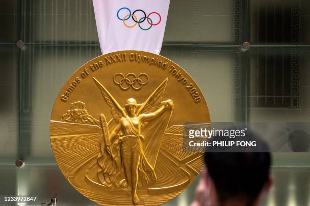 Man takes pictures of a large-scale reproduction of the Tokyo 2020 Olympic Games gold medal as part of the Olympic Agora event at Mitsui Tower in...