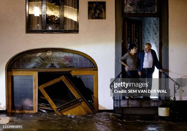 Man and woman stand on the stoop of their home as they look at the flood waters following heavy rains in Geulle on July 14, 2021. - Netherlands OUT /...