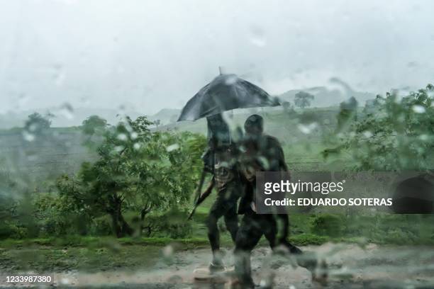 In this photograph taken through a window, members of the Amhara militia walk under an umbrella during heavy rain on a rural area northeast from the...