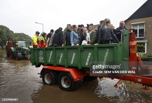 People ride on a trailer as the Dutch fire brigade evacuate people from their homes in South Limburg flooded by the rising waters from the Geul River...