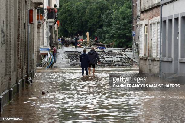 People make their way through water on a flooded street on July 15, 2021 in the Belgian city of Verviers, after heavy rains and floods lashed western...